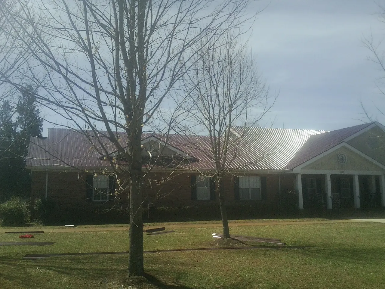 Red metal roof on a brick building seen from the front lawn in Eyota