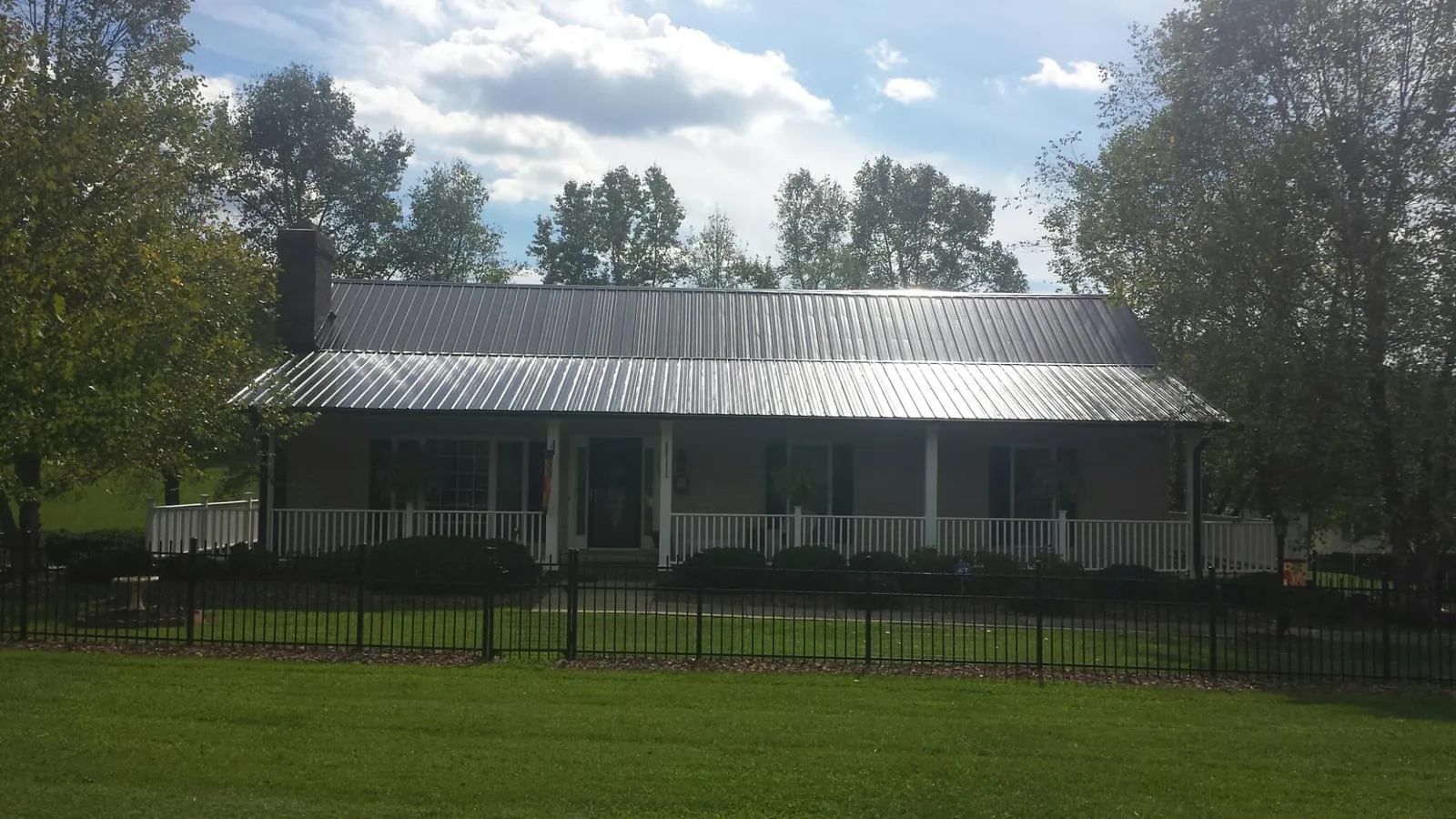 Gray metal roof on a brick ranch with a full width front porch — Gutter Guard Installation work by our crew in Eyota