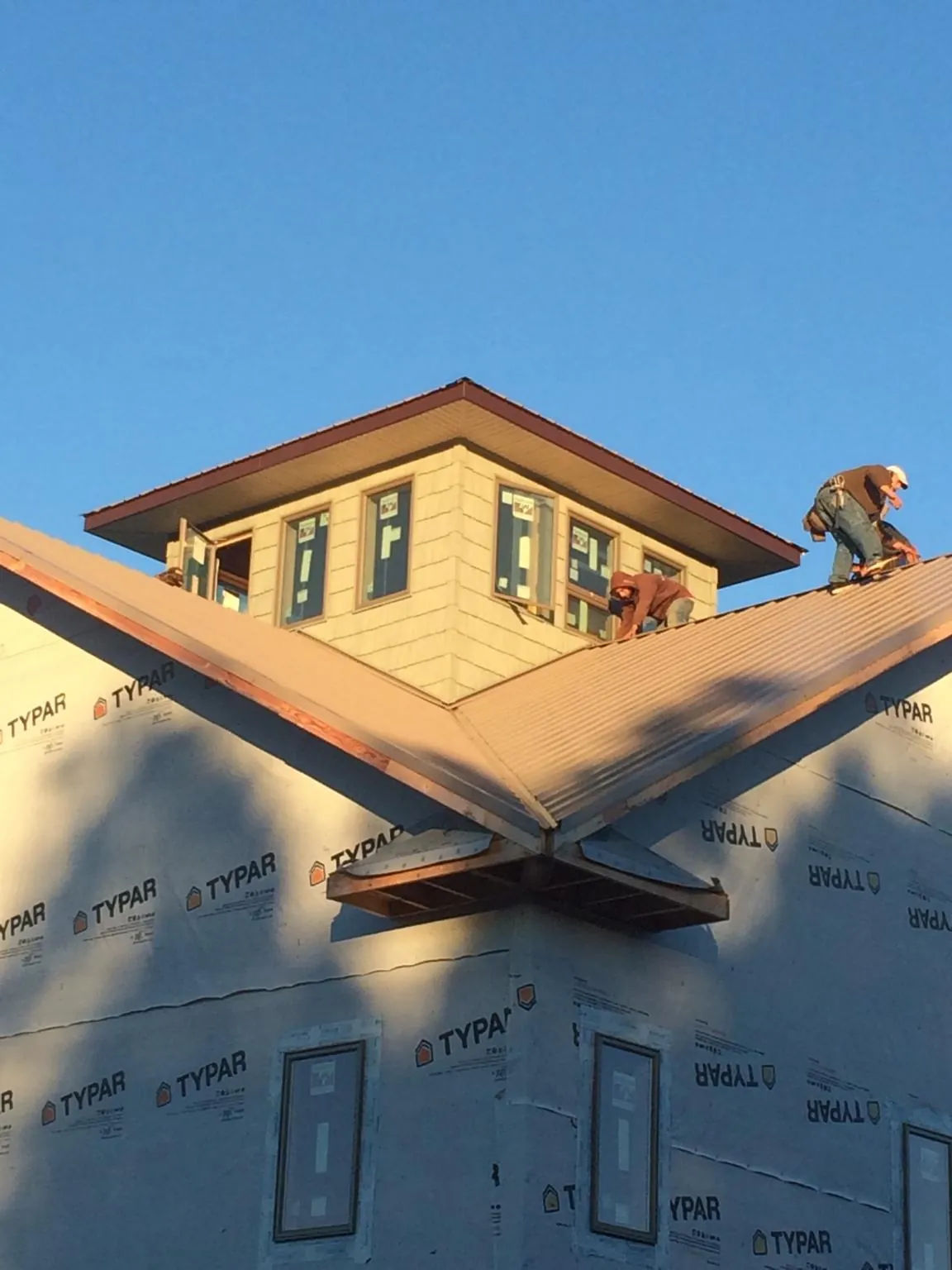 Roofers working around a rooftop cupola on a new metal roof at sunset — Roof Waterproofing in Eyota by Roofing Brothers